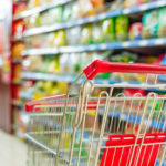 Supermarket interior, empty red shopping cart.