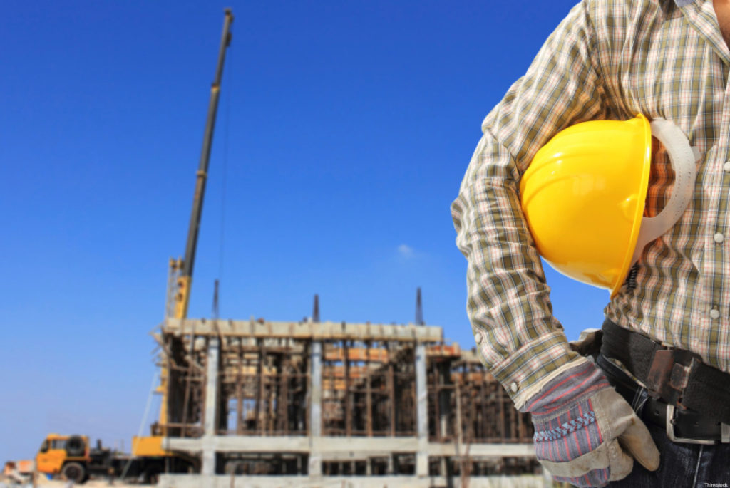 Worker and the blurred construction against blue sky