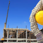 Worker and the blurred construction against blue sky