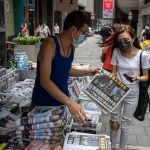 epa09281729 A woman buys a copy of Apple Daily newspaper at a news stand in Hong Kong, China, 18 June 2021. The pro-democracy newspaper made print-run of 500,000 for 18 June 2021, a day after Hong Kong?s national security police arrested five directors at the newspaper on suspicion of conspiracy to collude with foreign forces under the China-imposed legislation.  EPA/JEROME FAVRE
