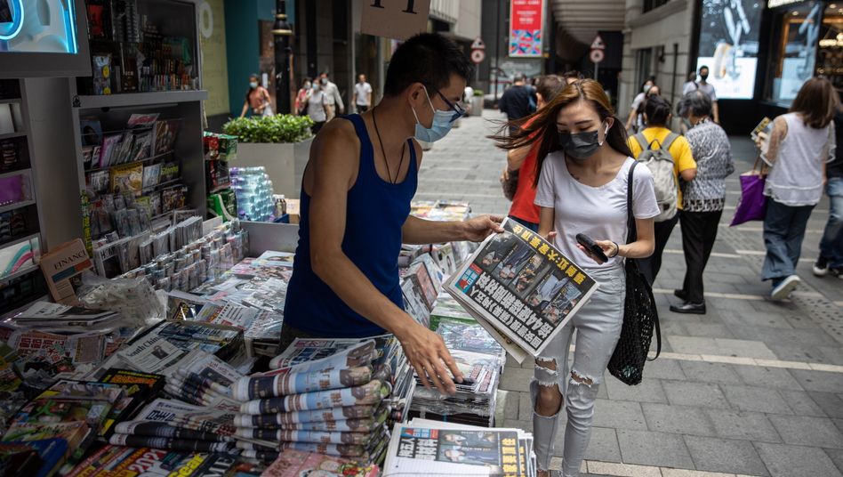epa09281729 A woman buys a copy of Apple Daily newspaper at a news stand in Hong Kong, China, 18 June 2021. The pro-democracy newspaper made print-run of 500,000 for 18 June 2021, a day after Hong Kong?s national security police arrested five directors at the newspaper on suspicion of conspiracy to collude with foreign forces under the China-imposed legislation. EPA/JEROME FAVRE